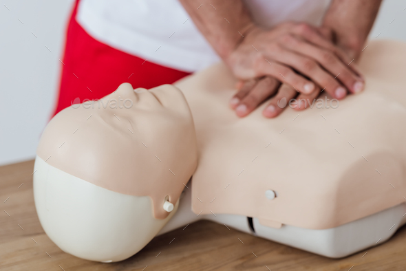 cropped view of man using chest compression technique on dummy during cpr training