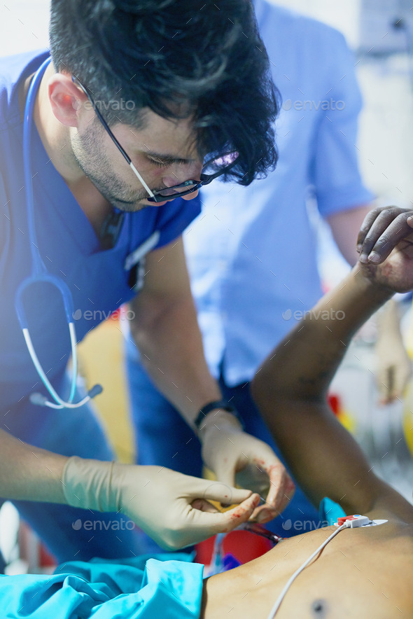 Shot of a doctor inserting a tube into a patients chest in an emergency room