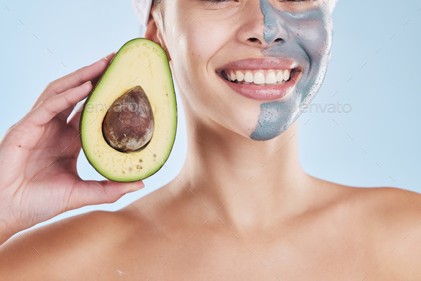 Beautiful young mixed race woman wearing a face mask peel and posing with an avocado isolated in st