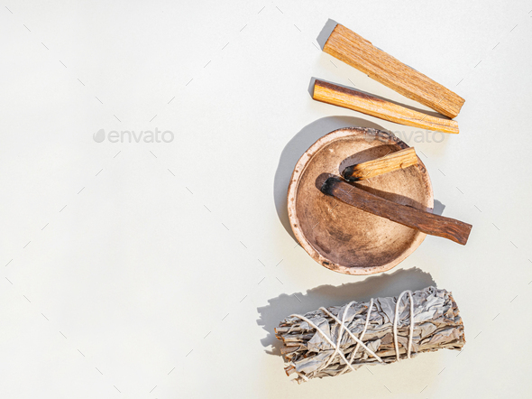 Items for spiritual cleansing - sage bundle, palo santo incense sticks on white background.