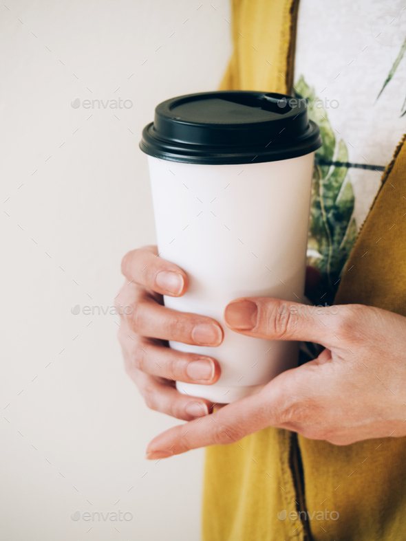 Female hands holding paper cup of coffee for logo on white background.
