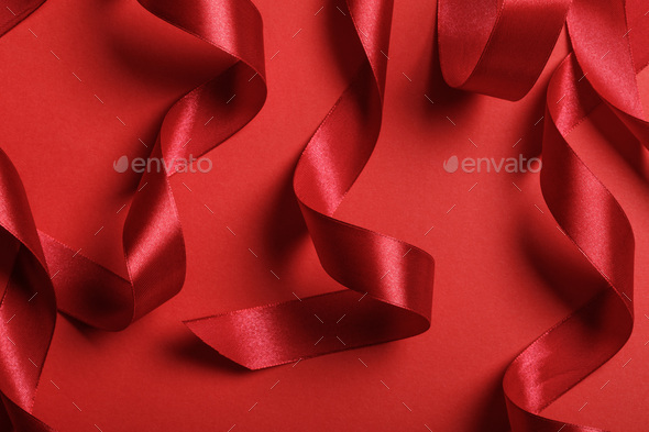 close up of curved satin red ribbons on red background Stock Photo