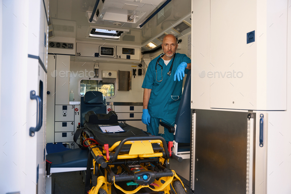 Emergency medical worker is standing inside a modern ambulance