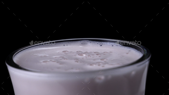 Close-up of strawberry milkshake on black isolated background. Frame. Milky pink cocktail with thick