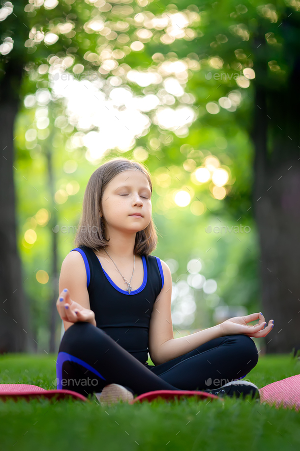 meditation in the park in the lotus position little girl meditates and ...