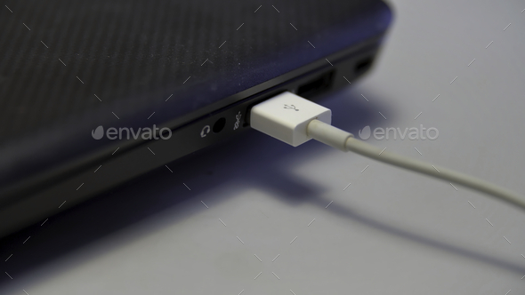 Hand inserting white USB cable into laptop isolated on white background. Media. Close up of