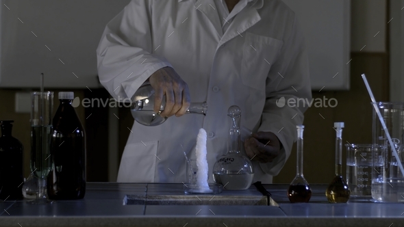Chemical reaction. Measuring glass with ice on a table of a chemical laboratory. Glass flask with
