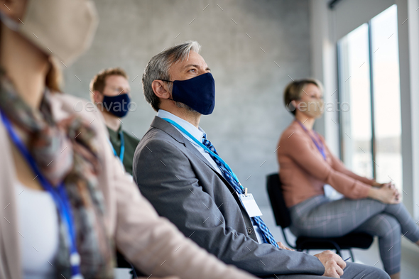 Entrepreneur with face mask attending business seminar during coronavirus pandemic.