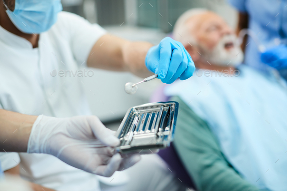 Close-up of dentist using angled mirror during dental examination at dentist;s office.