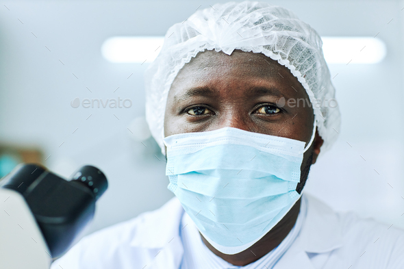 Black man wearing face mask and looking at camera working in laboratory