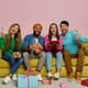 Young people celebrating birthday while sitting on the couch against pink background - PhotoDune Item for Sale