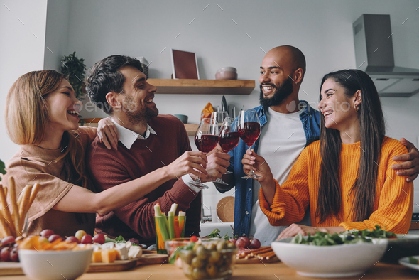 Happy young people toasting with wine while having dinner at home together - Stock Photo - Images
