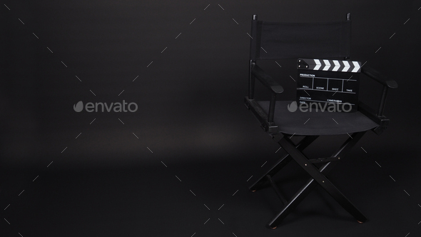 Black Clapperboard with director chair on black background.