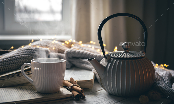 Cozy composition with a teapot, a cup and a book on a blurred background.