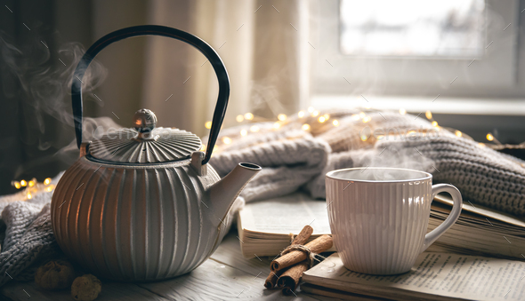 Cozy composition with a teapot, a cup and a book on a blurred background.