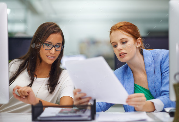 When in doubt, ask for advice. Shot of two attractive females looking over some work documents.