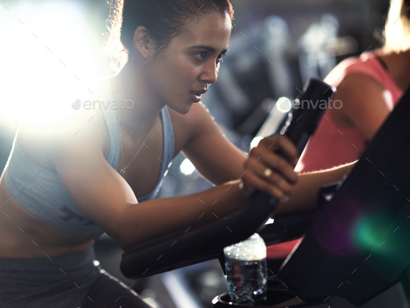 Shot of a determined looking young woman working out on an elliptical machine in the gym