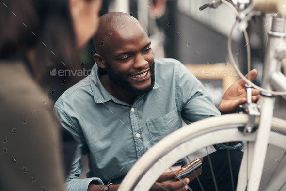 Shot of a handsome young man crouching down and looking at a bicycle before buying it