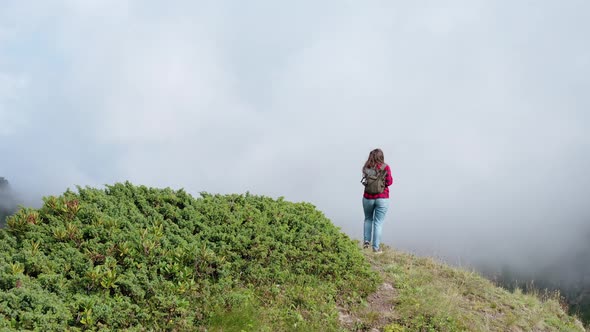 Woman Enjoys Lifting on Steep Mountain Top Over Tent Camp