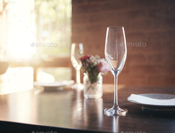 Empty glass on table for wine, champagne or alcohol at dinner in romantic restaurant, home or diner