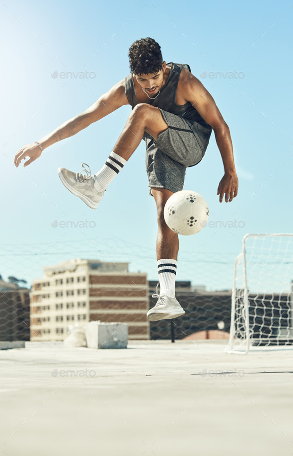 Soccer, skill and man athlete training with a ball for a game or exercise on rooftop in the city. F