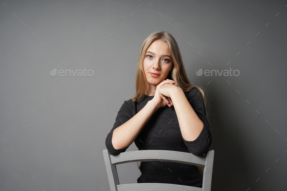 serene young woman sitting astride on chair - Stock Photo - Images