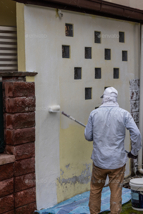 Painter worker adding undercoat foundation paint onto wall with roller