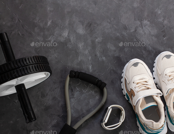 Sport equipment flatlay composition, white sneakers,sports watch,fitness chest expander, ab wheel