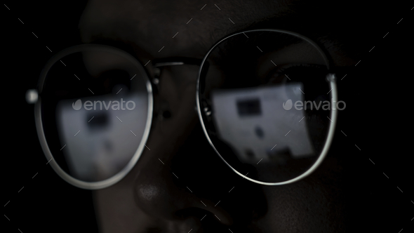 Close up of the eyes of a man with glasses at the computer isolated on black background. Concept