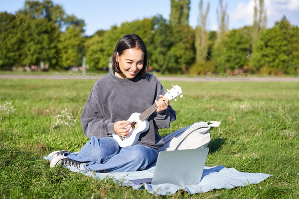 Happy young asian woman with casual clothing playing ukulele