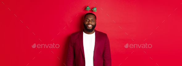 Merry Christmas. Happy african american man celebarting New Year, wearing funny party headband and