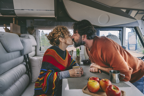 Love and kiss couple inside camper van during travel adventure vacation. Lifestyle van life