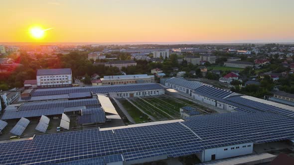 Aerial View of Blue Photovoltaic Solar Panels Mounted on Industrial Building Roof for Producing alt