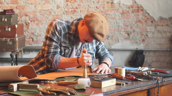 Handsome Young Shoemaker Cutting Leather in Workshop with Special Knife. alt
