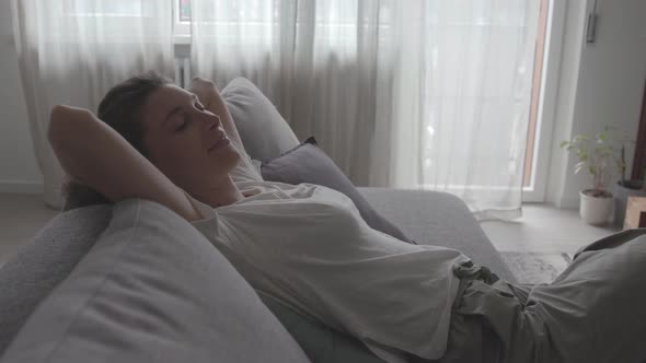 Happy relaxed woman lying on the sofa at home