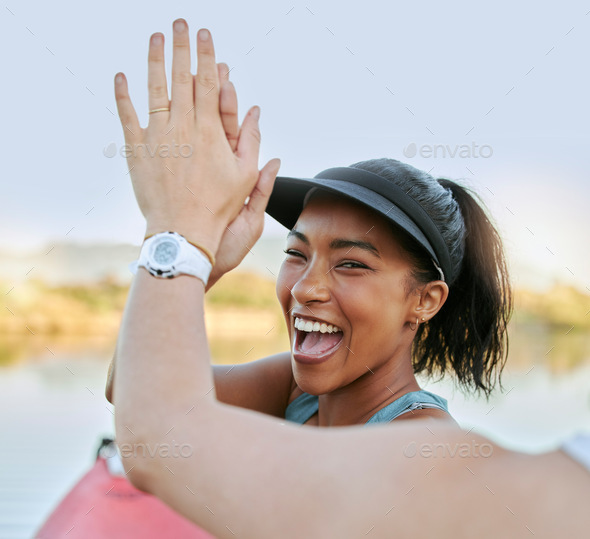 Close up of two friends giving high five while being active outdoors. Cheerful woman being positive