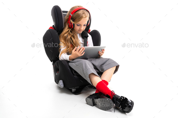 european girl listening to music and looking at a tablet on a machine chair on a white studio