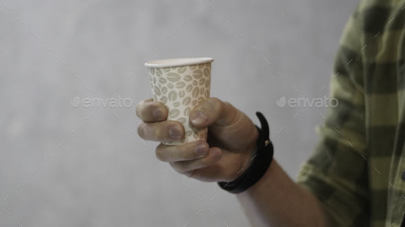 Man holding white cup then it changed to paper cup for coffee. A man is holding a brown paper cup