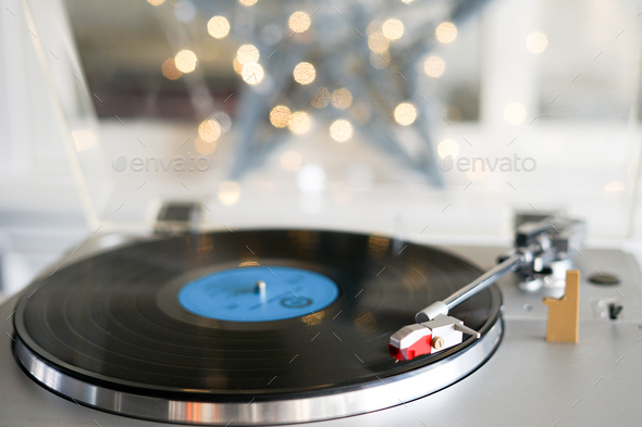 Close-up of vinyl record player, playing Christmas carols. Bokeh lights in the background. - Stock Photo - Images