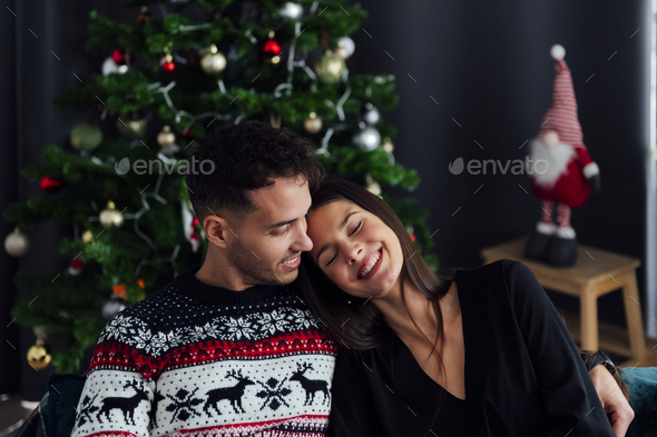smiling couple cuddling on the sofa at home at christmas time - Stock Photo - Images