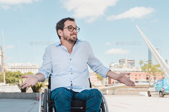 adult man outdoors sitting in wheelchair with frown and i don\'t care expression