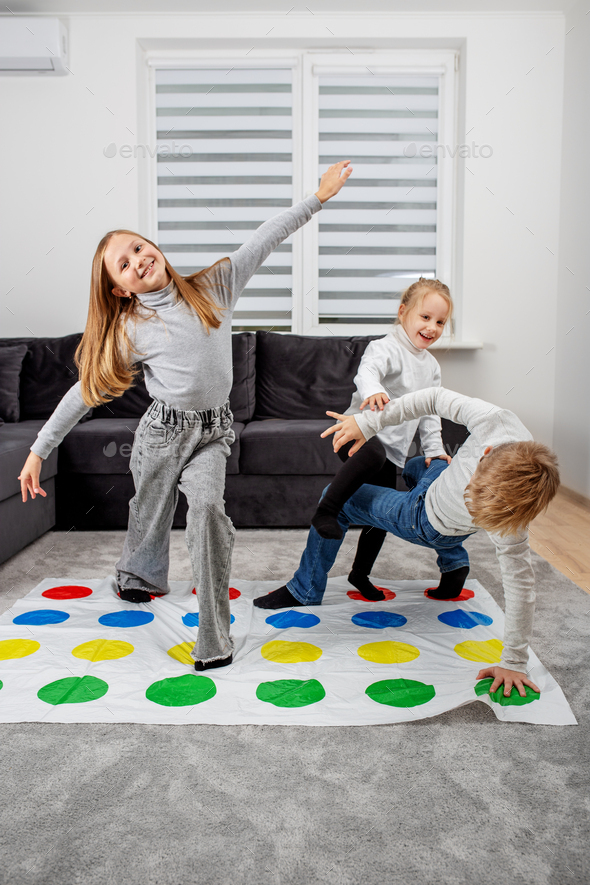 Group of children playing twister game and having fun. Concept of family and active leisure