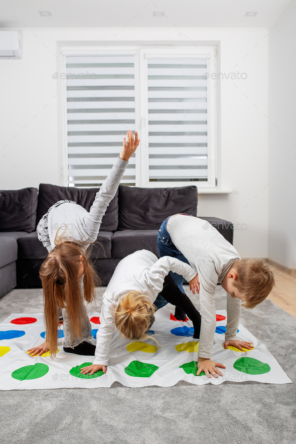Group of children playing twister game and having fun. Concept of family and active leisure