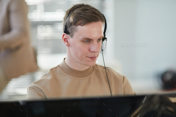 Young man wearing headset and looking at computer screen