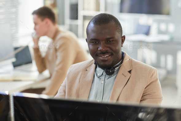 Smiling black man looking at computer in customer support center