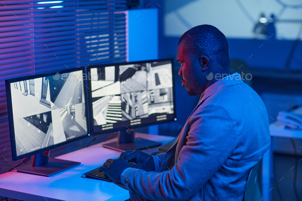 Black man looking at surveillance camera footage in security center office