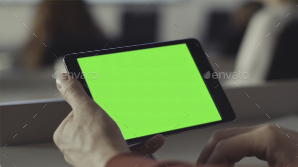 Man looks at the screen of the tablet with a green screen. Stock. Chroma key on the screen of the - Stock Photo - Images