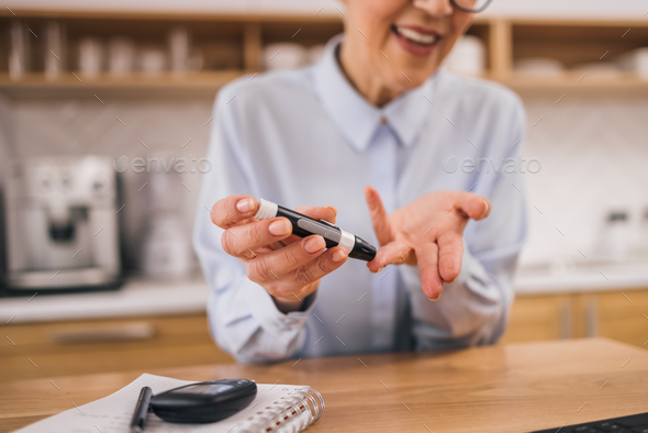 Senior woman using blood glucose monitoring device, close-up.