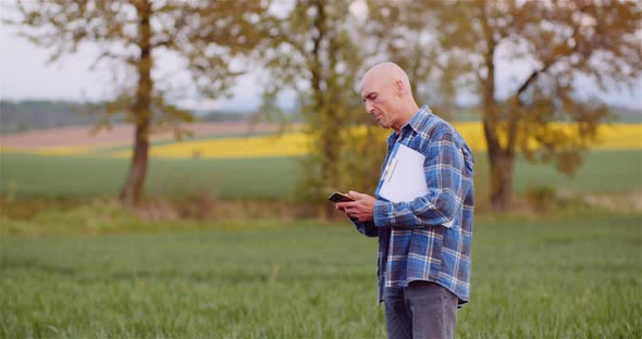 Farmer Talking on Mobile Phone While Working in a Field Agriculture alt