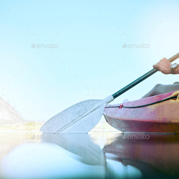 Closeup of kayak oar paddle rowing on calm water. Female hands kayaking on a lake during summer bre